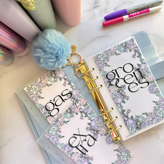 Open planner with floral design on a marble surface with stationery items.